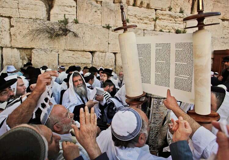 Jewish men hold up a Torah scroll before participating in a blessing during the Jewish holiday of Passover