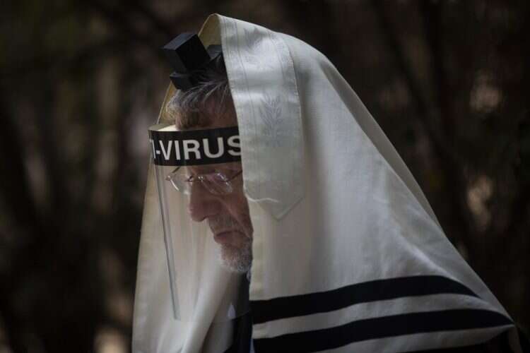 An ultra-Orthodox Jewish man wears a face mask during a morning prayer next to his house as synagogues are limited to 20 people due to the coronavirus pandemic, Sept. 24, 2020