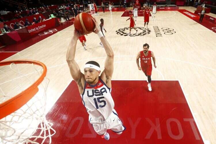 United States' Devin Booker (15) dunks the ball ahead of Iran's Mohammadsamad Nik Khahbahrami (14) during a men's basketball preliminary round game at the 2020 Summer Olympics, July 28, 2021, in Saitama, Japan