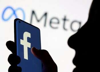 Woman holds smartphone with Facebook logo in front of Facebook's new rebrand logo Meta in this illustration picture