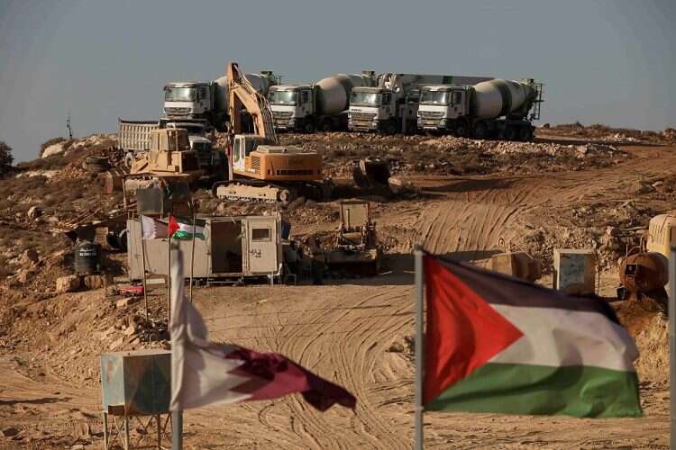 Construction trust are seen behind a Palestinian flag at the site for the Palestinian urban project Rawabi in the village of Atara, near Ramallah, on Dec. 29, 2010