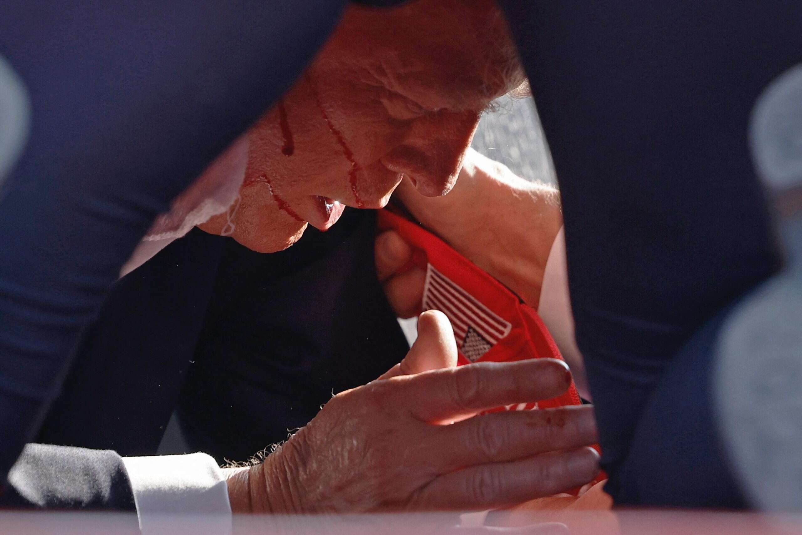 Trump can be seen under Secret Service agents covering him (Anna Moneymaker/Getty Images)