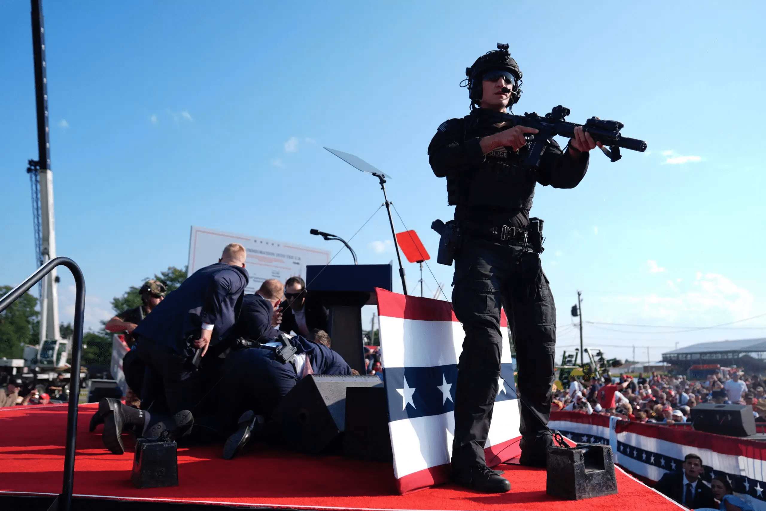 Trump is covered by Secret Service agents after loud bangs were heard at the rally (Evan Vucci/AP)