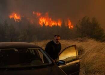 A resident quickly gets into his vehicle to escape the wildfire in Dione