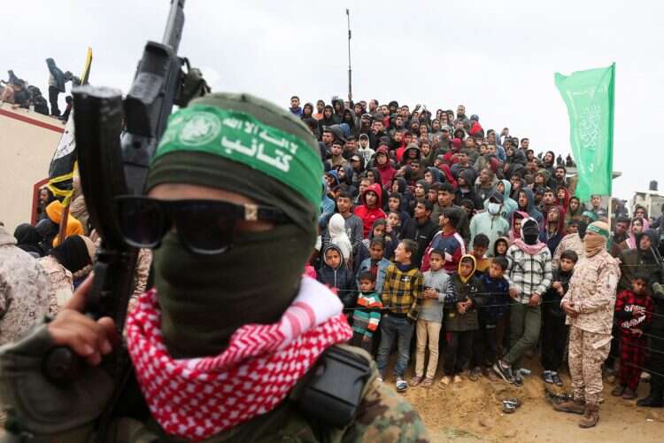 Palestinians look on during the handover by Hamas of deceased hostages