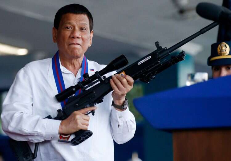 Philippine President Rodrigo Duterte jokes to photographers as he holds an Israeli-made Galil rifle at Camp Crame in suburban Quezon city northeast of Manila, Philippines on April 19, 2018